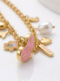Gold charm necklace with a pink heart charm, a pearl bead, and a heart-shaped tag engraved with 'AMOUR' on a white background.