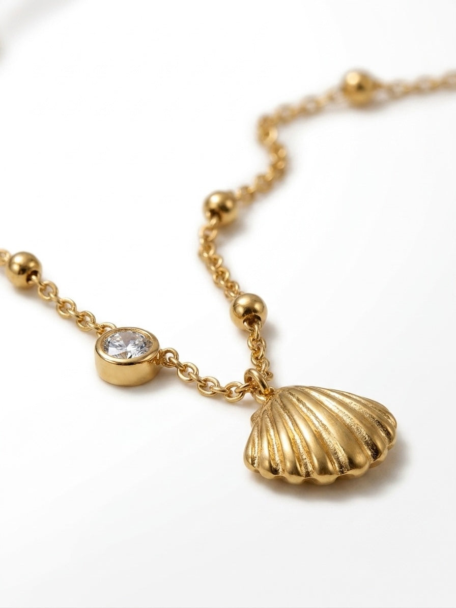 Shell Offset — gold satellite chain necklace with ridged scallop shell pendant and offset bezel-set crystal charm