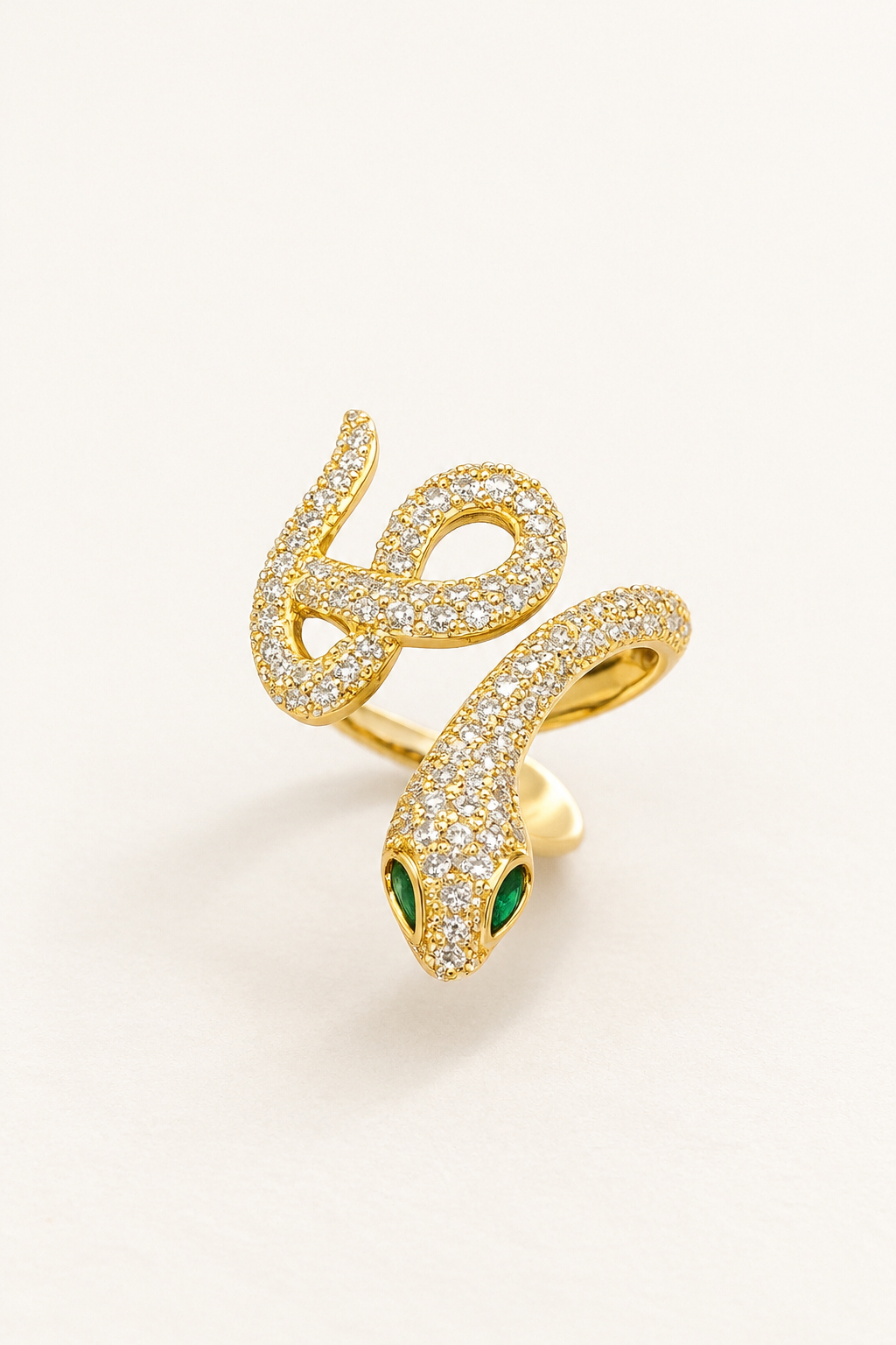 Gold-tone coiled serpent statement ring with pavé-style detailing and green eye accents