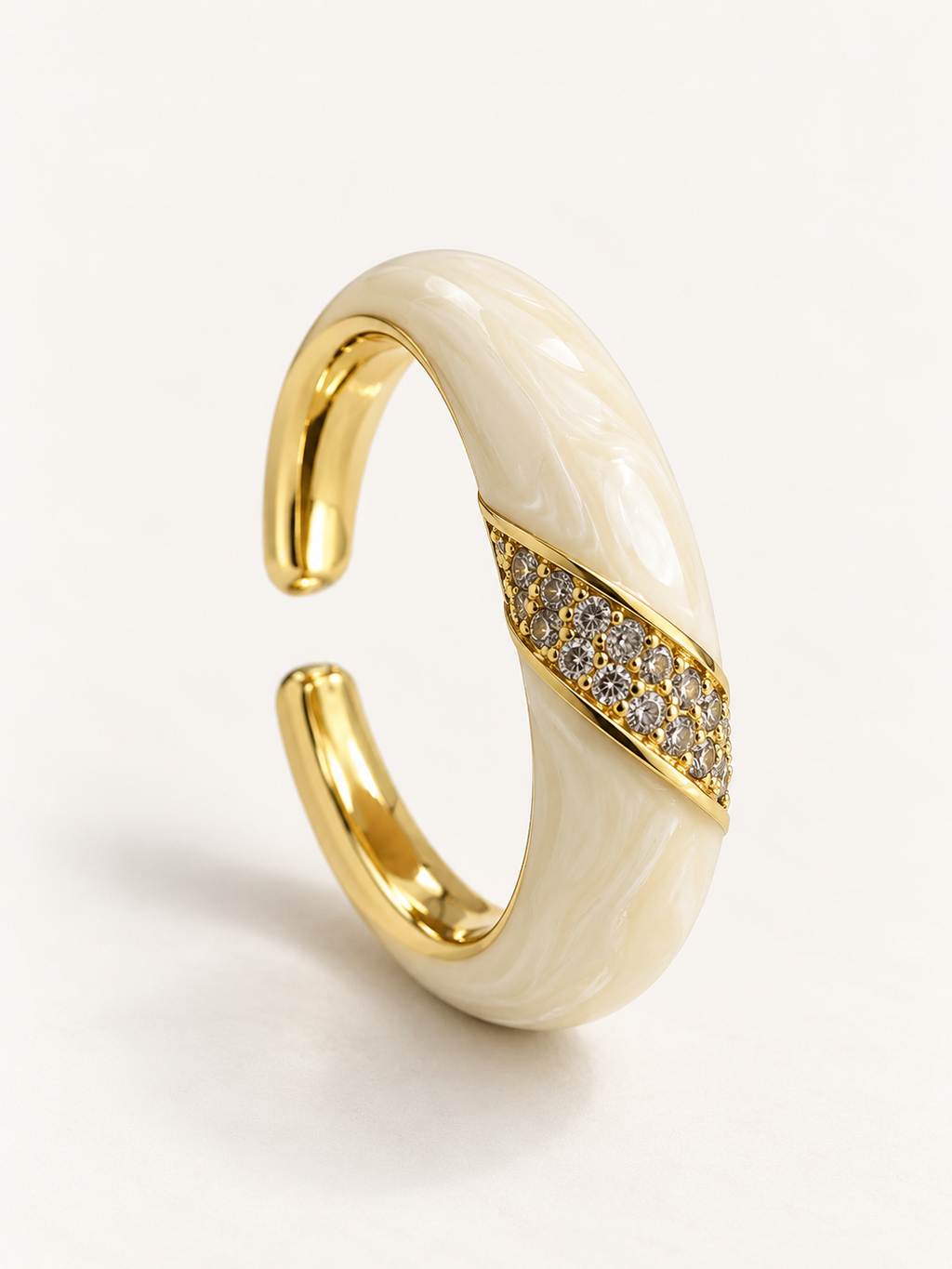 Cream-coloured open ring with gold-tone edges and a diagonal band of clear accents