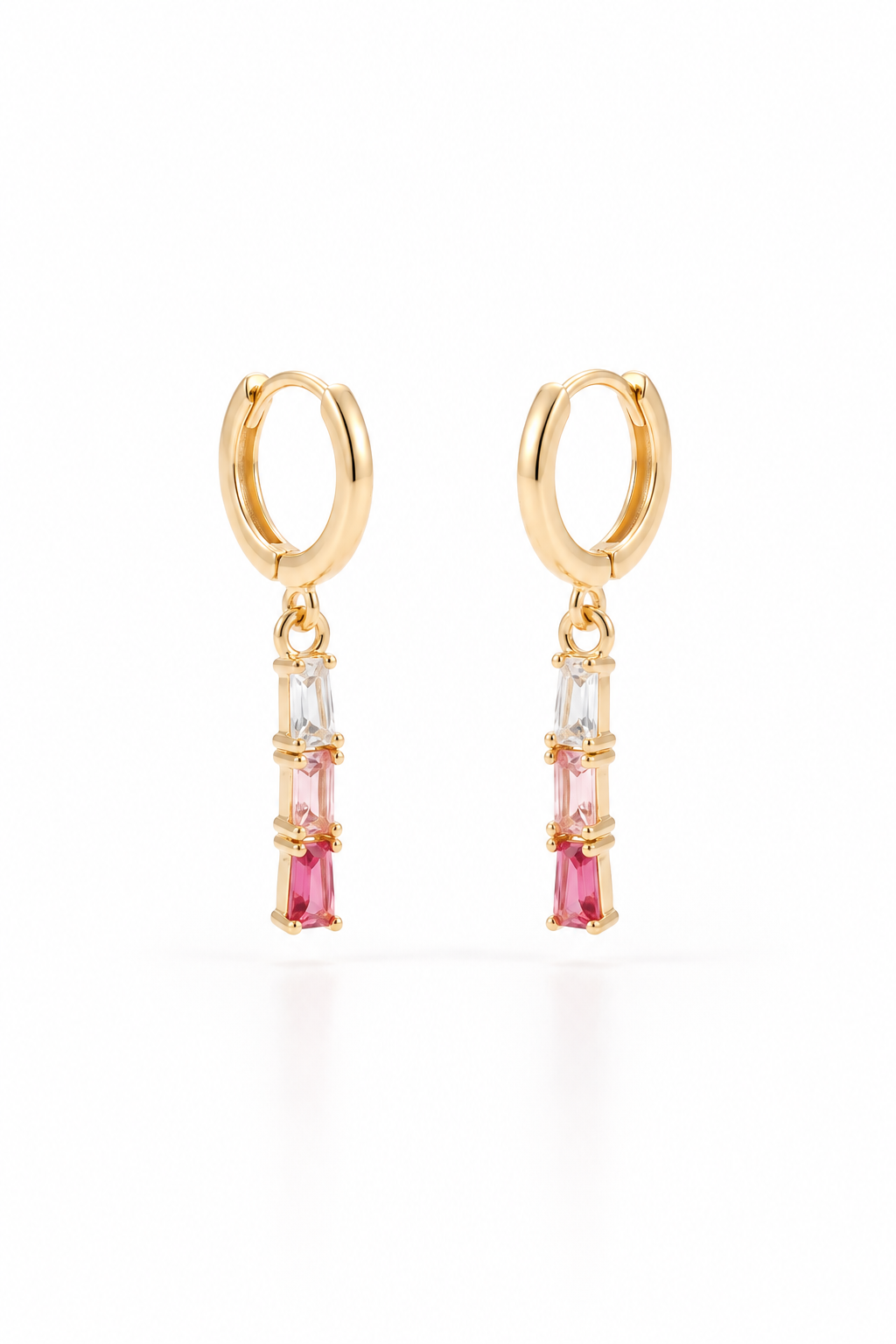 A pair of gold huggie hoop earrings with vertical dangle charms featuring a clear baguette stone, a pink baguette stone, and a larger pink marquise baguette stone, set against a plain white background.