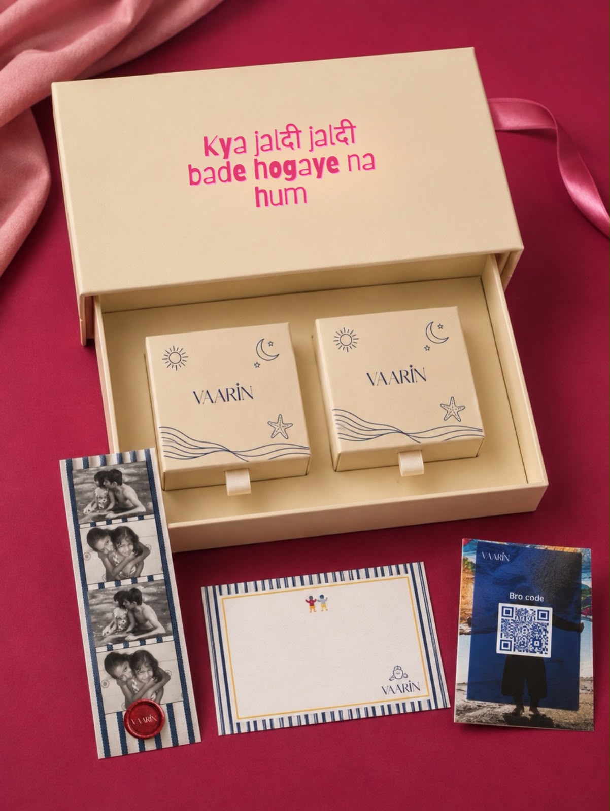 A personalized RAKHI gift set, featuring two small cream-colored boxes inside a larger cream-colored gift box with Hindi text. The boxes are decorated with simple navy blue line drawings of suns, moons, and stars, and are personalized with the name 'VAARIN'.